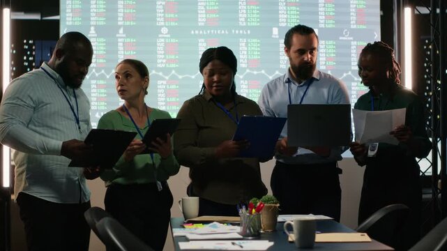Portrait of diverse business colleagues reviewing monthly insights and performance indicators within the company. Employees conducting evaluations and sharing ideas for goal setting. Camera B.