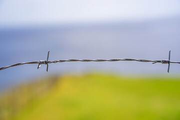 Barbed wire with blurred background in rural environment.