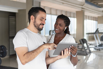 Personal trainer showing something on tablet to a client in the gym