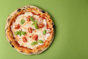 Delicious pizza with tomatoes and basil on green table, top view. Space for text