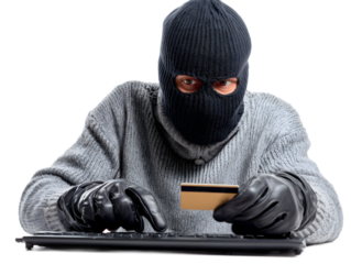 Cybercriminal wearing a balaclava and gloves using a computer keyboard while holding a credit card, representing identity theft, online fraud, cybercrime, and digital financial hacking, isolated on wh