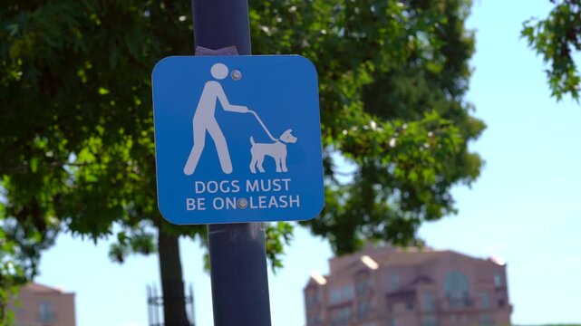 Dogs must be on leash sign sunny day trees park