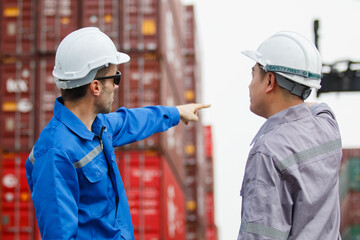 Team of engineers or workers at a container yard discussing seriously and shaking hands to symbolize teamwork and business success.