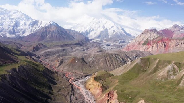 Incredible aerial 4K flying drone footage of mountain river with tributaries surraunded green hills deep in Pamir mountains with Lenin peak 7134m, Kyrgyzstan, Central Asia