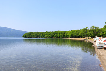 Boats at Rest: Lakeside Serenity with White Rowboats and Forest Reflections