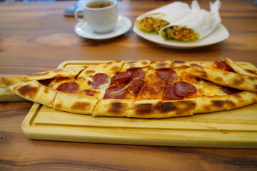 Pepperoni Pide, Wraps, and Coffee on Shared Meal Table