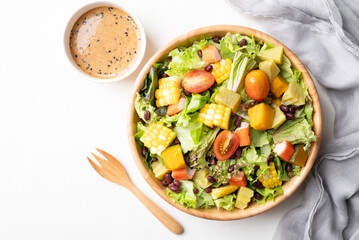 Top view of healthy vegetable salad in wooden bowl with Japanese sesame dressing on white background