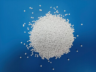 plastic masterbatch, white masterbatch granules as virgin polymer resin pigment, poured into blue background media, suitable for industrial plastic company profile product catalog design