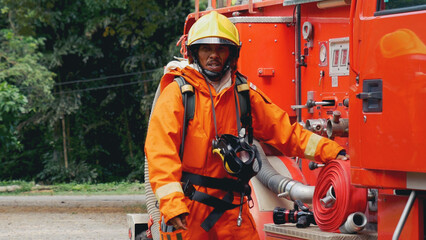 Fireman prepare equipment at fire engine truck. Man hand connect water tube with fire truck...
