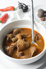 Overhead view of Nigerian goat pepper soup in a white soup plate, top view of goat meat pepper soup in a plate, traditional goat peppersoup in a white bowl