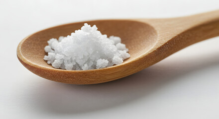 Delicate crystalline sea salt piled gracefully on a crafted wooden spoon showcasing texture