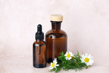 Three brown glass bottles arranged artfully alongside a basket of chamomile flowers. Natural aesthetic ideal for herbal remedies. Alternative medicine, healthy and well-being theme concept