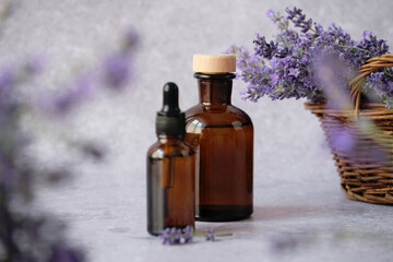 Two amber glass bottles filled with lavender essential oil displayed alongside fresh lavender sprigs. Alternative medicine, healthy and well-being concept