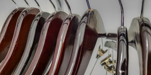 wide abstract close-up of sleek wooden hangers, hanging in a closet, coat check cloakroom or retail area. organization and interiors design element or background