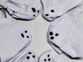 Creative concept of spooky Halloween ghosts made from crumpled lined paper, representing discarded ideas or mistakes arranged in a circle.