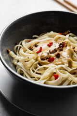 top view of creamy peanut sauce on noodles, overhead view of peanut noodles in a grey bowl