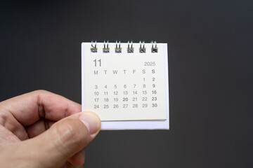 Hand Holding Desk Calendar for NOVEMBER 2025 background. Calendar concept with 2025 NOV calendar on...