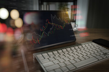 Stock trading decision concept visualized by candlestick and trend charts on a tablet as a trader monitors real-time market data at a digital workspace with keyboard and smartphone.