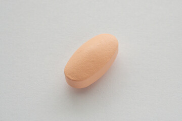 Orange vitamin pill tablet on white background