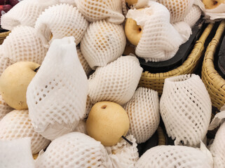 Top angle shot of yellow pears wrapped with Polyethylene foam in grocery store. A pile of pears covered by a fruit net to protect them from bumps and scratches. Graphic Resources. Negative space