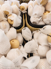 Top angle shot of yellow pears wrapped with Polyethylene foam in grocery store. A pile of pears covered by a fruit net to protect them from bumps and scratches. Graphic Resources. Negative space