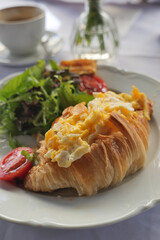 Croissant with eggs and salad served in a cafe