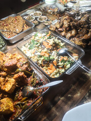 Side view of a food buffet at a budget restaurant. Indonesian dishes are served on trays and plates and stacked on the food rack. Food buffet at a Warteg-style eatery. Culinary with copy space.