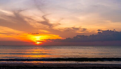 Obraz premium Fiery Sunset Over Calm Ocean Waves at Beach