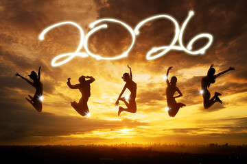 Group of people jumping joyfully in silhouette with a glowing 2026 text at sunset.