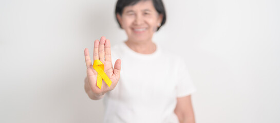 Elderly with Yellow Ribbon for concept of yellow September, Suicide prevention day, Childhood, Pediatric, bone and bladder cancer Awareness month, support survivor. Healthcare and World Cancer day
