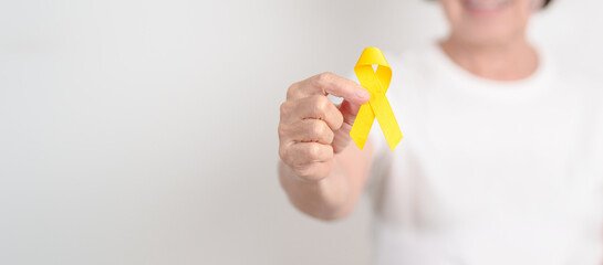Elderly with Yellow Ribbon for concept of yellow September, Suicide prevention day, Childhood, Pediatric, bone and bladder cancer Awareness month, support survivor. Healthcare and World Cancer day