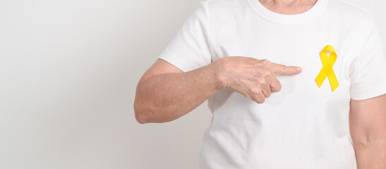 Elderly with Yellow Ribbon for concept of yellow September, Suicide prevention day, Childhood, Pediatric, bone and bladder cancer Awareness month, support survivor. Healthcare and World Cancer day