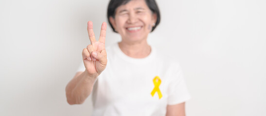 Elderly with Yellow Ribbon for concept of yellow September, Suicide prevention day, Childhood, Pediatric, bone and bladder cancer Awareness month, support survivor. Healthcare and World Cancer day
