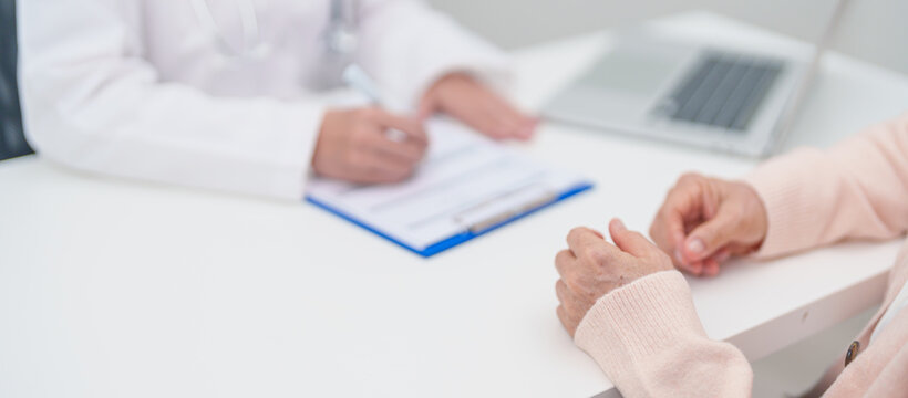 senior woman consulting with doctor in hospital. Elderly patient talking and sharing disease. Doctor listens, asking question and taking note. medical consultation and geriatric Healthcare concept