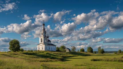 A historic church is situated in a vibrant green field, surrounded by trees and under a striking blue sky filled with fluffy clouds. The scene radiates tranquility and beauty.