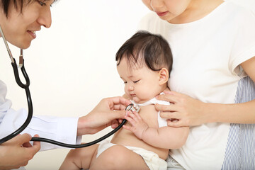 お母さんに抱かれ、聴診器で診察される赤ちゃん