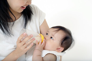 赤ちゃんを抱き、哺乳瓶で授乳する母親