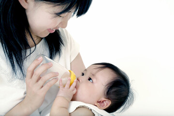 赤ちゃんを抱き、哺乳瓶で授乳する母親