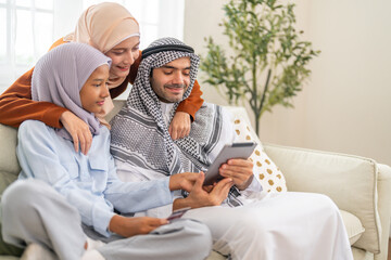 Muslim family learning online use tablet for homeschool education, daughter engaged in e-learning while parents guide with modern knowledge digital, online entertainment and muslim kids development