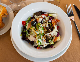Appetizing salad with avocado and smoked salmon in sauce served on platter