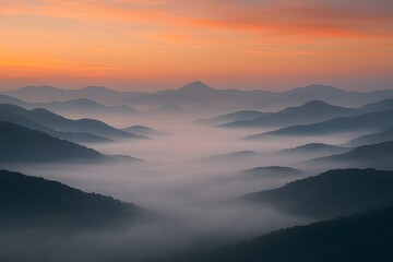 Misty mountain valley at sunrise with orange sky