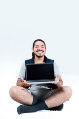 Smiling man sitting showing computer screen on white background
