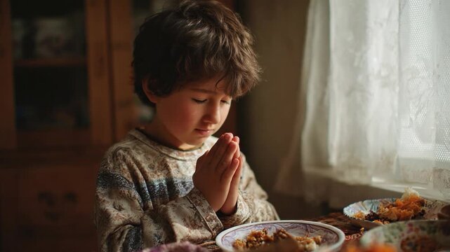 Prayer of Gratitude: A young boy, with eyes closed and hands clasped in a gesture of prayer, expresses heartfelt gratitude over his meal, in a simple yet poignant portrayal of faith and thankfulness.