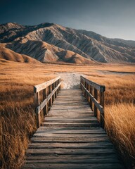 Wooden bridge leading to a mountain range under a clear sky