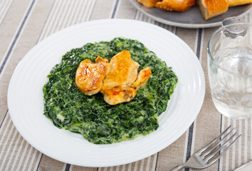 Healthy dinner of baked chicken fillet slices served with spinach stewed in thick and luscious white bechamel sauce..