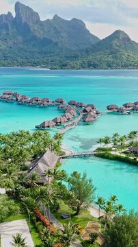 Bora Bora, French Polynesia. Luxury Resort and Overwater Bungalows Overlooking Lagoon and Main Island, Vertical Drone Shot