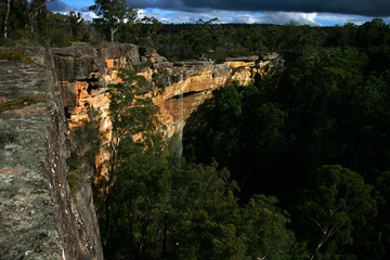Cascading waterfall over striking orange rock in the Australian bush.