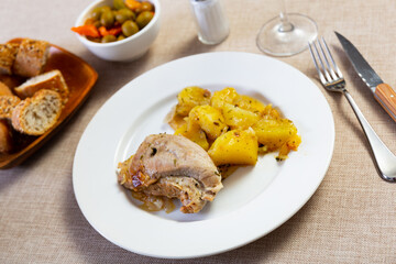Stewed pork and cut potato pieces served in a plate with other table appointments