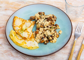 Tasty scrambled eggs with asparagus, mushrooms and pancakes
