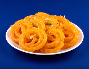 Fresh orange jalebi dessert in white bowl on bright background. Generative AI
